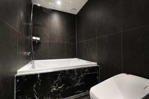 a black bathroom with a tub and a toilet at Mari Hotel in Chungju