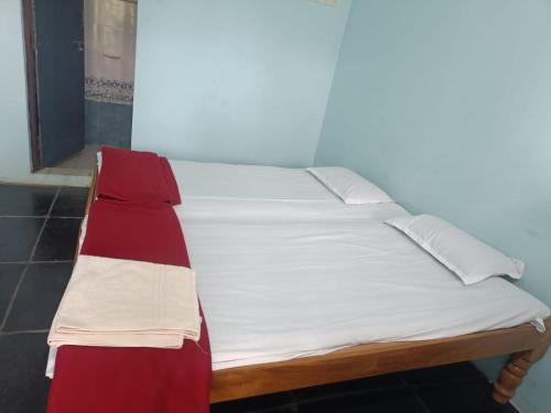 Best Home stay Hampi Anegundi في هامبي: سرير في غرفة شراشف بيضاء وحمراء