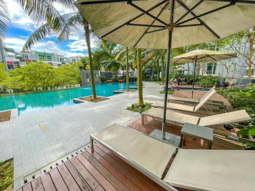 una piscina al aire libre con bancos y sombrillas junto a un complejo en 1Medini Theme Suite by Nest Home【LEGOLAND】 en Nusajaya