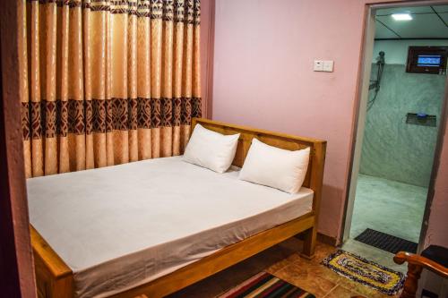 a small bedroom with a bed and a shower at PENGIRIWATTA REST INN in Kamburugamuwa