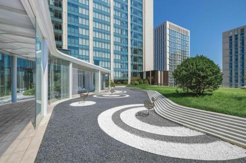 a park with a bench and some tall buildings at The Westin Yantai in Yantai