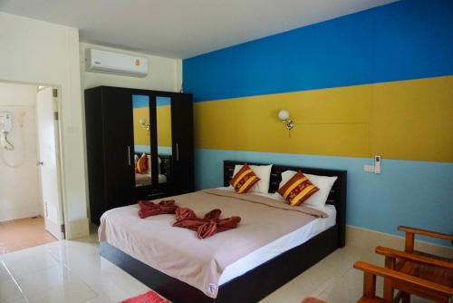- une chambre avec un grand lit aux murs bleus et jaunes dans l'établissement Smilebeach Resort Khaolak, à Khao Lak