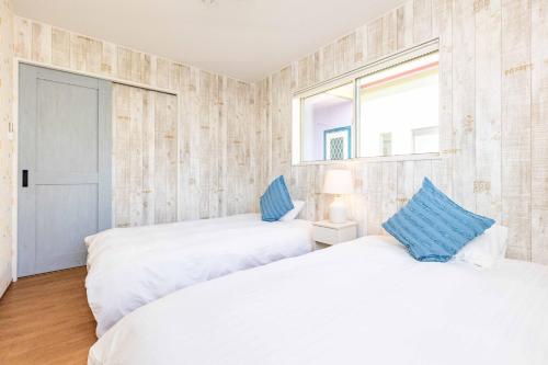 two white beds in a room with a window at Nanki Shirahama Angel in Shirahama
