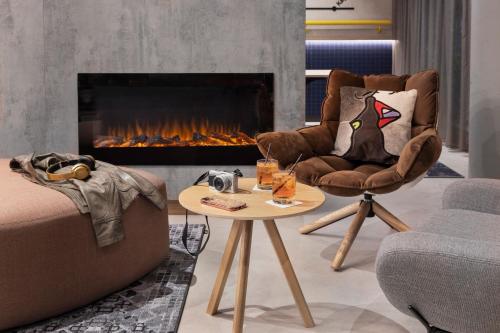 a living room with a fireplace and a chair and a table at Moxy Vienna City East in Vienna