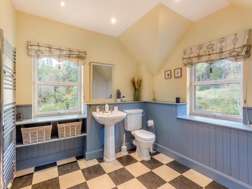 a bathroom with a toilet and a sink and two windows at Ardachy in Lewiston