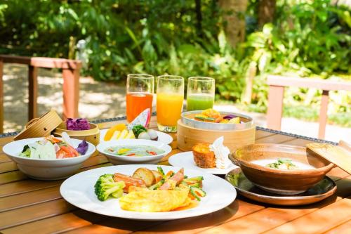 una mesa con platos de comida y vasos de jugo de naranja en Coco Garden Resort Okinawa, en Uruma