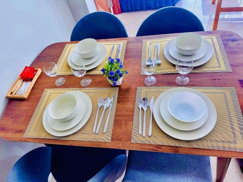 een houten tafel met witte borden en bestek erop bij vortex suites klcc Adela Suites in Kuala Lumpur