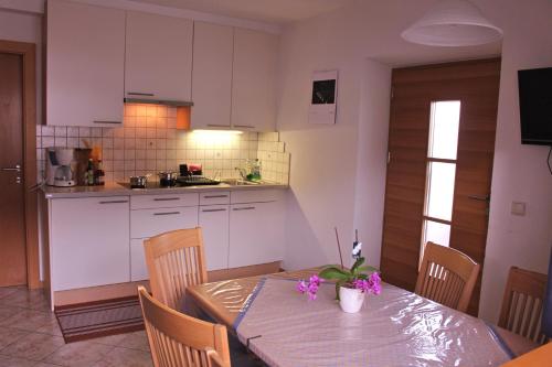 una cocina con una mesa con flores púrpuras. en Appartements Schatzer, en Valdaora