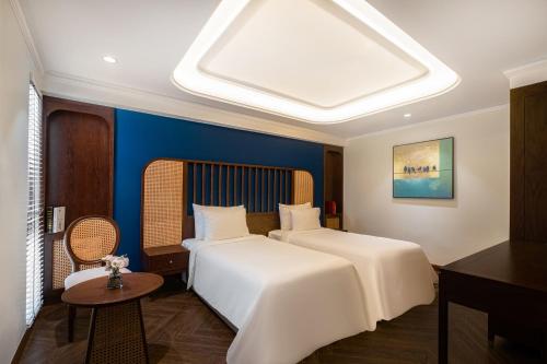 a hotel room with two beds and a table at La Siesta Classic Hang Thung in Hanoi