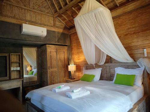 a bedroom with a large white bed with green pillows at Tangkas wooden house in Tampaksiring