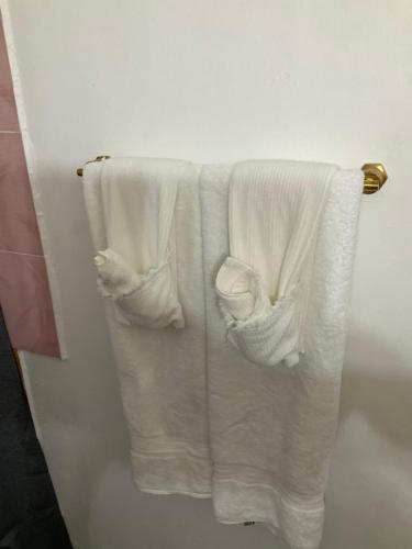 three white towels hanging on a rack in a bathroom at Travelers Oasis in Portmore
