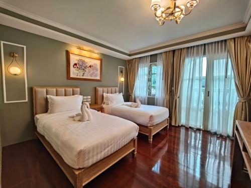 a hotel room with two beds and a chandelier at Siri Grand Bangkok Hotel in Bangkok