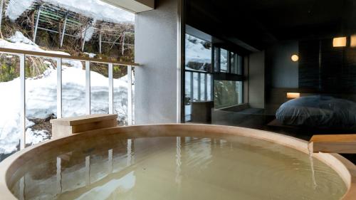 a bath tub in a room with a large window at Sake Hotel Tamakiya in Tokamachi