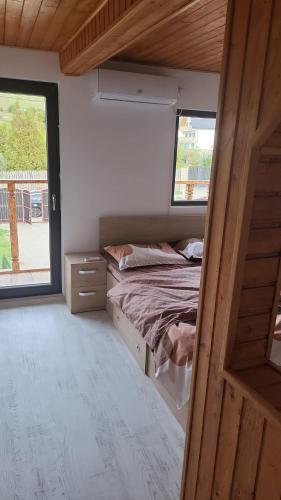 a small bedroom with a bed and two windows at CABANA ADAM SI EVA in Gura Râului