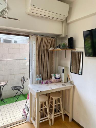 桜宿-ダブルベッドの小さなガーデンルーム في طوكيو: غرفة بها مكتب وبه جهاز كمبيوتر