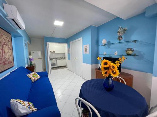 La casa di Dafne في مسينة: غرفة زرقاء مع أريكة زرقاء وطاولة مع الزهور