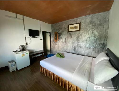 a bedroom with a white bed and a concrete wall at ม่านฟ้าฮิลล์ ภูชี้ฟ้า 