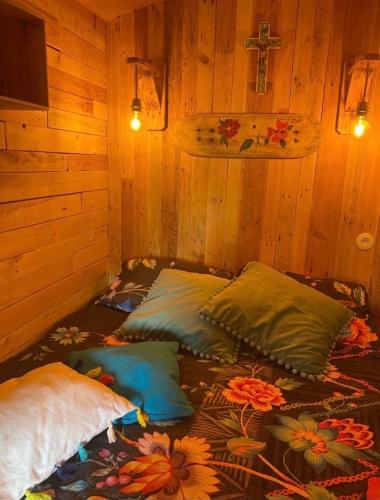 Cette chambre comprend 4 oreillers sur un lit avec une croix sur le mur. dans l'établissement Roulotte de Charme, à Bréconchaux