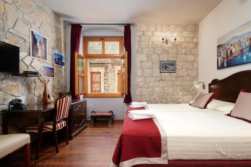 sypialnia z łóżkiem i biurkiem w pokoju w obiekcie Heritage Hotel Tragos w Trogirze