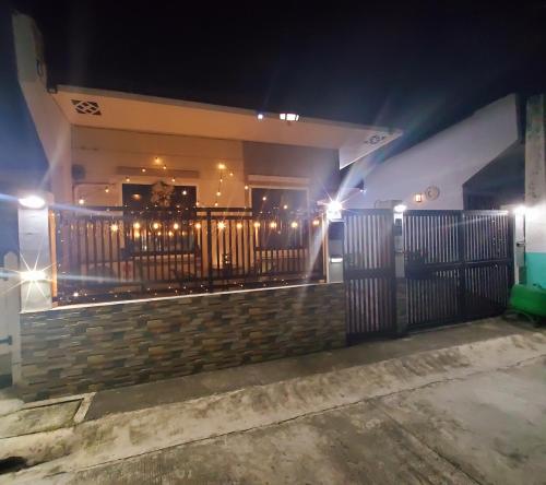 a building with a fence with lights on it at night at Cozy 2 Bedroom (Entire House) Pearson Residences in Hulugan