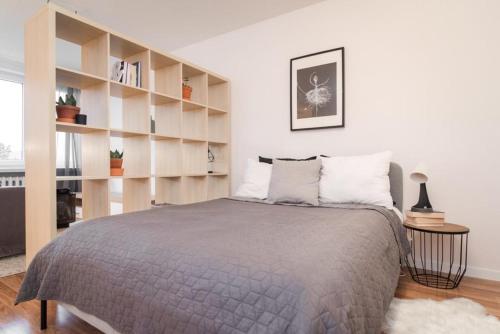 a bedroom with a bed and a book shelf at Apartament Okrzei in Płock