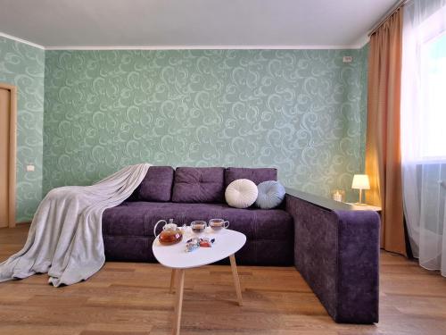 a living room with a purple couch and a table at ЕКО-квартира на Садововому. Мережа Alex Apartments. Цілодобове безконтактне заселення in Shcherbani