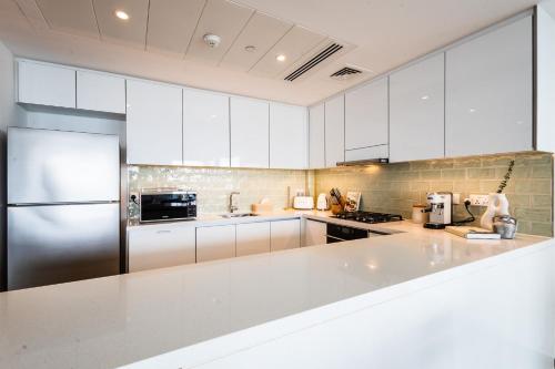a kitchen with white cabinets and a stainless steel refrigerator at Voyage 2 Bedroom In Mayan With Ocean Views in Abu Dhabi