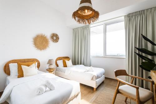 een slaapkamer met 2 bedden en een stoel bij Voyage 2 Bedroom In Mayan With Ocean Views in Abu Dhabi