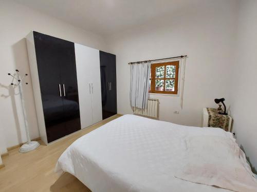 a white bedroom with a large bed and a window at Patagonia Relax in Comodoro Rivadavia