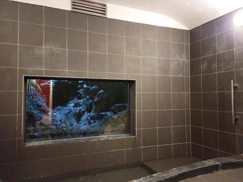 a bathroom with a fish tank on a tiled wall at Tsukimotoya Ryokan in Toyooka