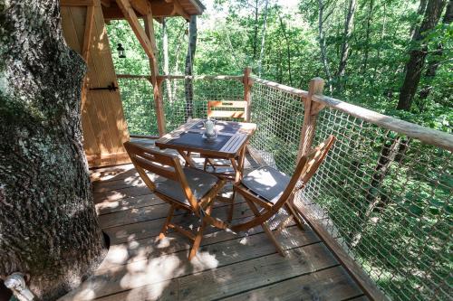 een tafel en twee stoelen op een houten terras bij Les Cabanes de Fontfroide in Saint-Antoine