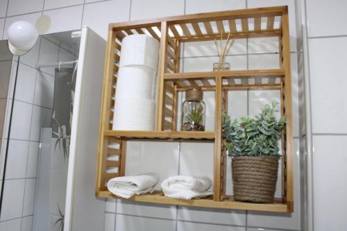 uma prateleira de madeira numa casa de banho com toalhas e uma planta em Ruhiges & schickes 4 Zi-Apartment em Heilbronn