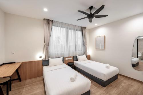 a hotel room with two beds and a ceiling fan at Codrington House - Boutique Apartments in George Town