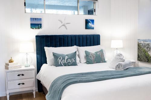 a bedroom with a bed with a blue headboard and pillows at Caloundra Poolside Paradise in Caloundra