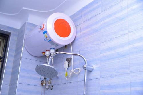 La salle de bains est pourvue d'une douche et d'un appareil blanc et orange. dans l'établissement 3 Bedroom Family Apartment, à Namulanda