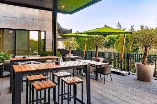 a patio with tables and chairs and an umbrella at Mezzo Hotel & Business in Beringen