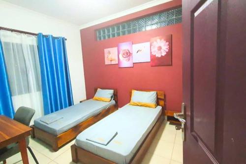 two beds in a room with a red wall at Les Alizés Appartement meublé 2 in Toamasina
