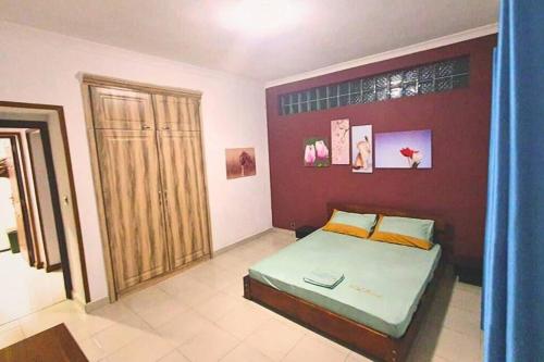 a bedroom with a bed and a red wall at Les Alizés Appartement meublé 2 in Toamasina