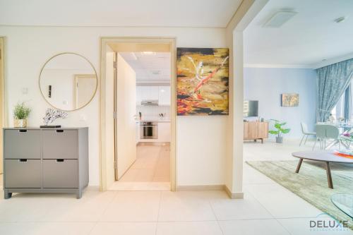 Chic 1BR at Al Bateen JBR by Deluxe Holiday Homes في دبي: غرفة معيشة مع مرآة ولوحة على الحائط