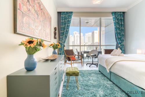 Chic 1BR at Al Bateen JBR by Deluxe Holiday Homes في دبي: غرفة نوم بسرير وطاولة مع إناء من الزهور