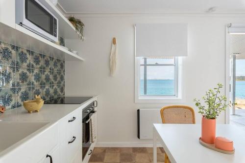 uma cozinha com um balcão branco e uma janela em Fogo @ Ethel & Ode’s em Bundeena