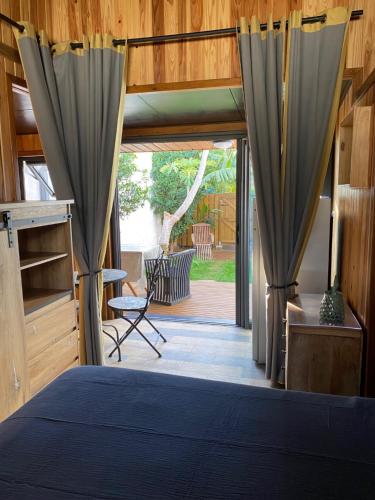 Schlafzimmer mit einem Bett mit Vorhängen und einer Terrasse in der Unterkunft Le Chalet du Domaine in La Saline-Les-Bains