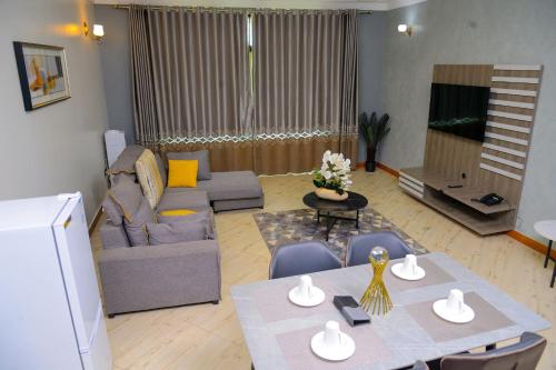 a living room with a table and a couch at 3 Bedroom Malaikanzi Apartment in Namulanda