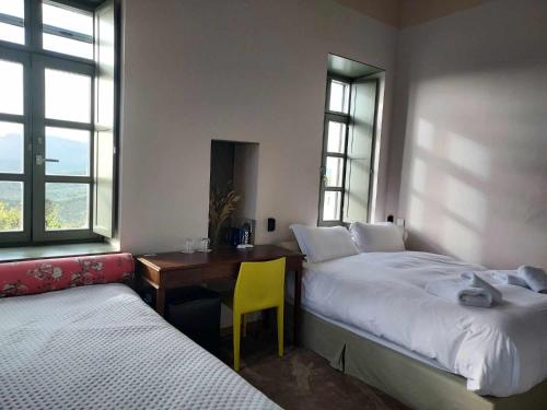 1 dormitorio con 2 camas y escritorio con silla amarilla en KATIKIA ZAGORI en Vítsa