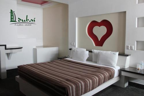 1 dormitorio con 1 cama con un corazón rojo en la pared en Motel Dubái Ensenada en Ensenada