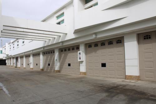 une rangée de portes de garage dans un bâtiment blanc dans l'établissement Motel Dubái Ensenada, à Ensenada