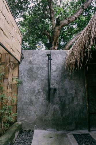 a shower in a wall next to a tree at west room at Semadi Living in Sukawati