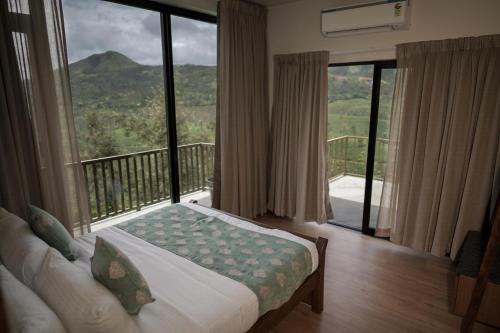 a bedroom with a bed and a balcony with a view at Tea & Tranquility in Vagamon