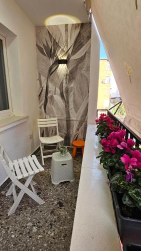 a balcony with two chairs and a wall with flowers at City Center Apartment in Tirana
