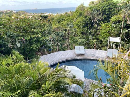 una piscina con 2 sillas y el océano en 4 bedrooms villa at Gustavia 500 m away from the beach with sea view private pool and enclosed garden, en Gustavia